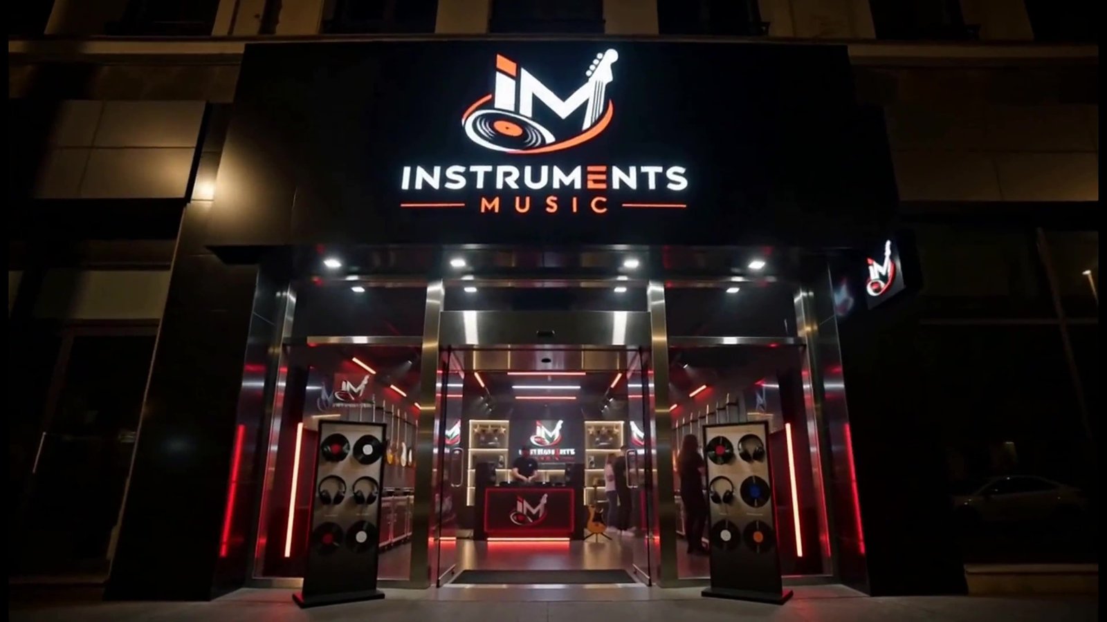 Devanture nocturne de la boutique Instruments Music, enseigne lumineuse en lettres blanches et rouge sur une façade sombre